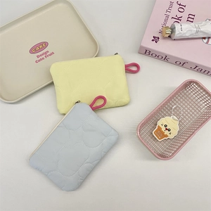 Close-up of heart-quilted texture on pastel yellow and blue nylon mini pouches