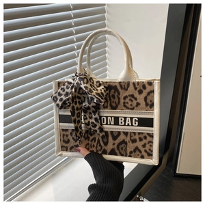 Detail of leopard print tote bag featuring white leather trim and Fashion Bag ribbon