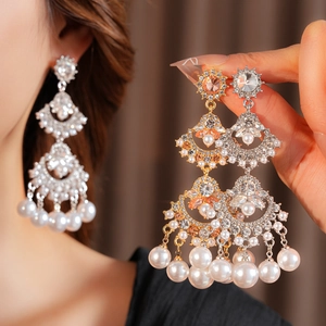 Detailed close-up of fan-shaped fringe earrings with pearls and crystal inlay work