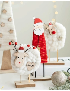Macro detail of wool felt reindeer and Santa decor with wood base and XMAS engraving