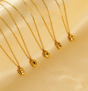Detailed macro of stainless steel bubble letter pendants on gold silk fabric background