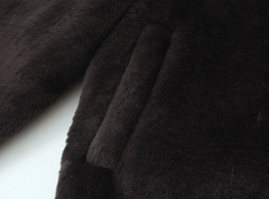 Detail of dark brown faux fur jacket showing high-quality pocket stitching and soft texture