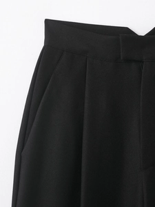 Détail du pantalon large noir montrant le tissu en sergé et les coutures de la poche