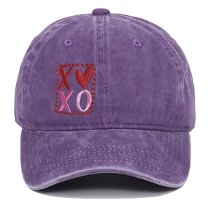 Detailed embroidery of XO and red heart on purple washed cotton baseball cap fabric