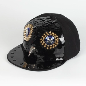Detail of hiphop flat brim hat featuring sequined owl with blue gems and metal studs
