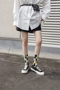 Close-up of stylish street style mid-calf socks with black, yellow, and green plaid pattern