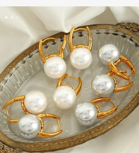 Detail of elegant gold pearl earrings on vintage tray with white silk background