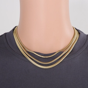 Close-up of triple-layered golden snake chain necklace on model with grey shirt