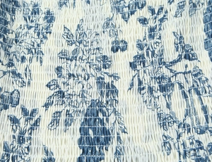 Detail of blue floral smocking fabric with elastic gathers on a slim-fit dress