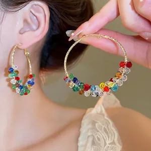 Elegant gold round earrings with colorful crystal beads and pearls shown on a model