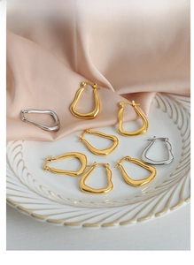 Detailed view of asymmetric geometric titanium steel earrings in gold and silver finish
