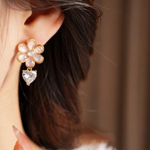 Close-up of model wearing pink floral heart drop earrings with gold plating and zircons