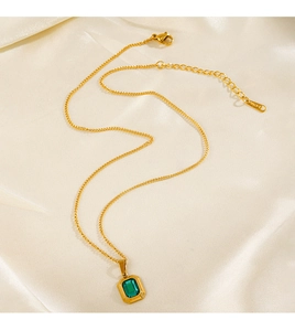 Dettaglio della collana placcata oro 18K con gemma quadrata verde su sfondo seta