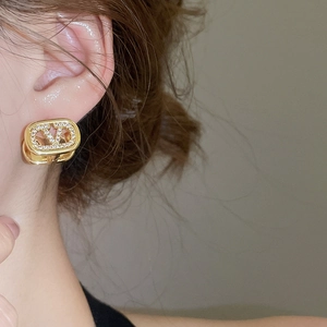 Macro view of 18k gold plated oval V-letter earring with zircon stones on the ear