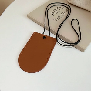 Close-up of a brown leather pull-out key holder and access card case on a white desk