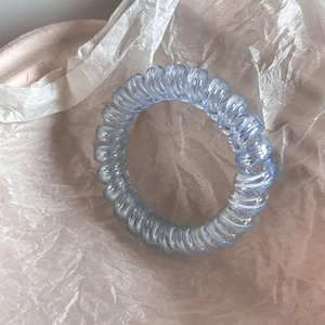 Detail of light blue translucent spiral hair tie with a flexible telephone cord design