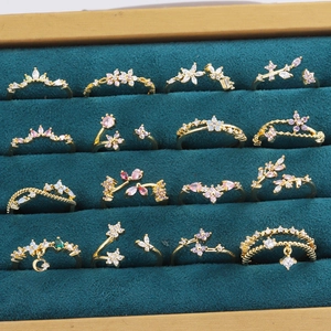 Ensemble de bagues dorées papillon et fleur avec cristaux sur fond de velours bleu