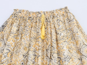 Detail of elastic waist with yellow tassel drawstring on floral printed woven skirt