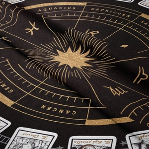 Detail of bohemian tapestry featuring gold zodiac patterns and tarot motifs on dark fabric
