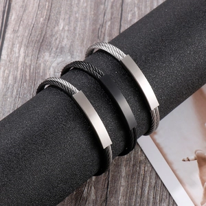Close-up of twisted cable steel bracelets with matte rectangular plates on a display