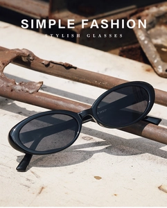 Close-up of retro oval sunglasses in black frame on a vintage industrial metal pipe