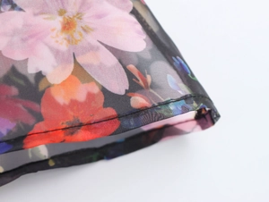 Detailed macro view of floral print organza fabric with fine stitching and translucent texture