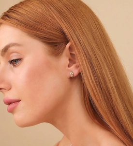 Close-up of elegant small gold hoop earrings with zircon pavé on a female model