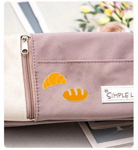 Détail de broches émaillées en forme de croissant et baguette sur un sac en toile