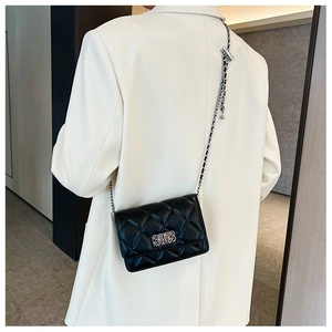 Detail of elegant black quilted chain crossbody bag shown on a model's shoulder
