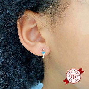Close-up of blue enamel star hoop earring in 925 sterling silver worn on ear