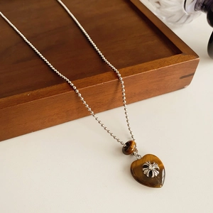 Detail of silver ball chain with heart resin pendant and cross flower engraving