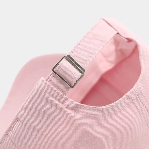 Detailed macro view of pink cotton twill baseball cap with adjustable metal buckle