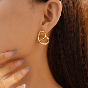 Detailed view of an 18k gold plated hollow heart-shaped earring worn on a model ear