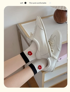 Close-up of white leather sneakers with red flower embroidery on soft cotton socks