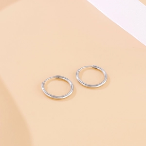 Close-up of polished silver stainless steel hoop earrings on soft silk ribbon background