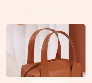 Detail of brown PU leather shell makeup bag with reinforced double handles and zipper