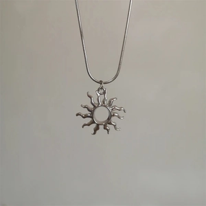 Detail view of silver sunburst pendant on a sleek snake chain necklace for women and men
