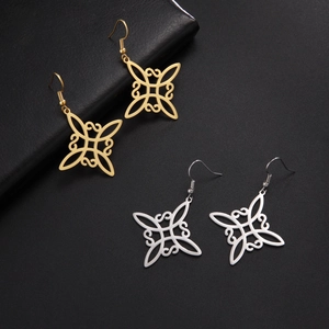 Symmetrische hohle Hexenknoten-Ohrringe in Gold und Silber auf schwarzem Lederboden