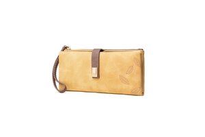 Macro detail of yellow leather wallet with leaf embossing and gold zipper closure