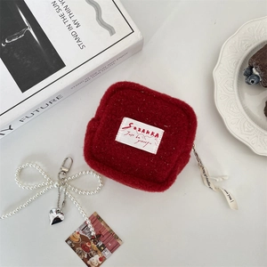 Detail of red plush storage pouch with pearl bow pendant and SOZAKKA logo tag