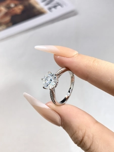 Detail of classic six-prong moissanite ring with side accent diamonds on a silver band