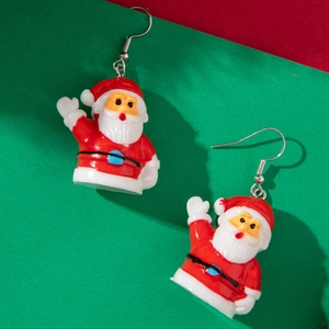 Close-up of Santa Claus earrings with red suit and white beard on a festive background