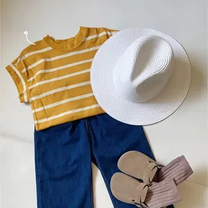 Flat lay di una maglietta a righe gialle per bambini con cappello di paglia e jeans