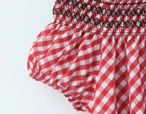 Détail de robe vichy rouge avec smocks à points de croix noirs et manches bouffantes