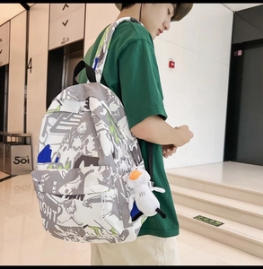 Detail of waterproof graffiti backpack featuring THE NIGHT text and a cute duck pendant