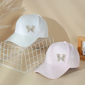 Detailed close-up of lace pattern fabric and rhinestone butterfly on baseball caps