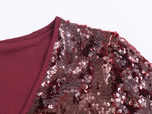Dettaglio dei lussuosi lustrini rosso vino e della scollatura a V del vestito