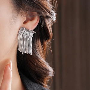 Gros plan de boucles d'oreilles à pampilles argentées portées par un mannequin