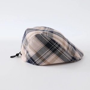Detail view of the beige and navy plaid ivy cap featuring an adjustable elastic drawstring