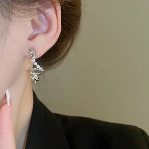 Macro shot of silver snake stud earring with zircon stones worn on the ear